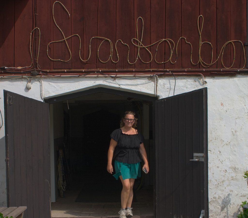 Annika kommer ut ur stallet i Svartarbo en varm sommardag.