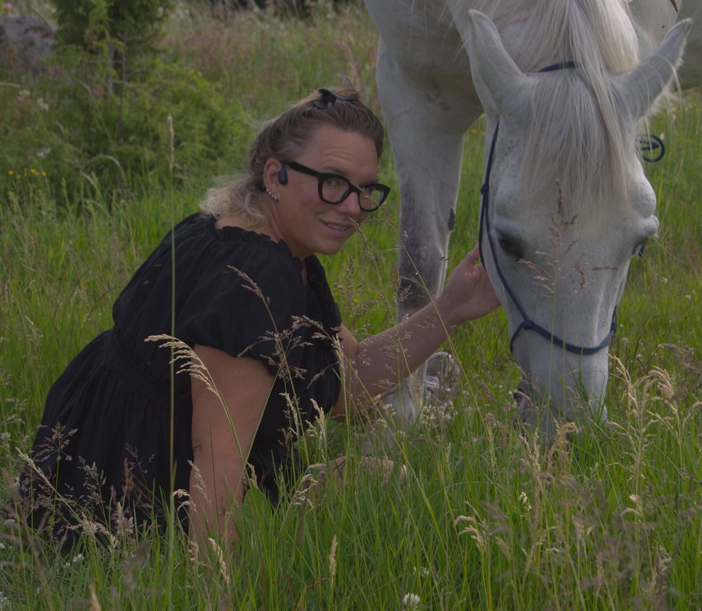Annika Lif sitter bredvid Wiggo som står och äter gräs.